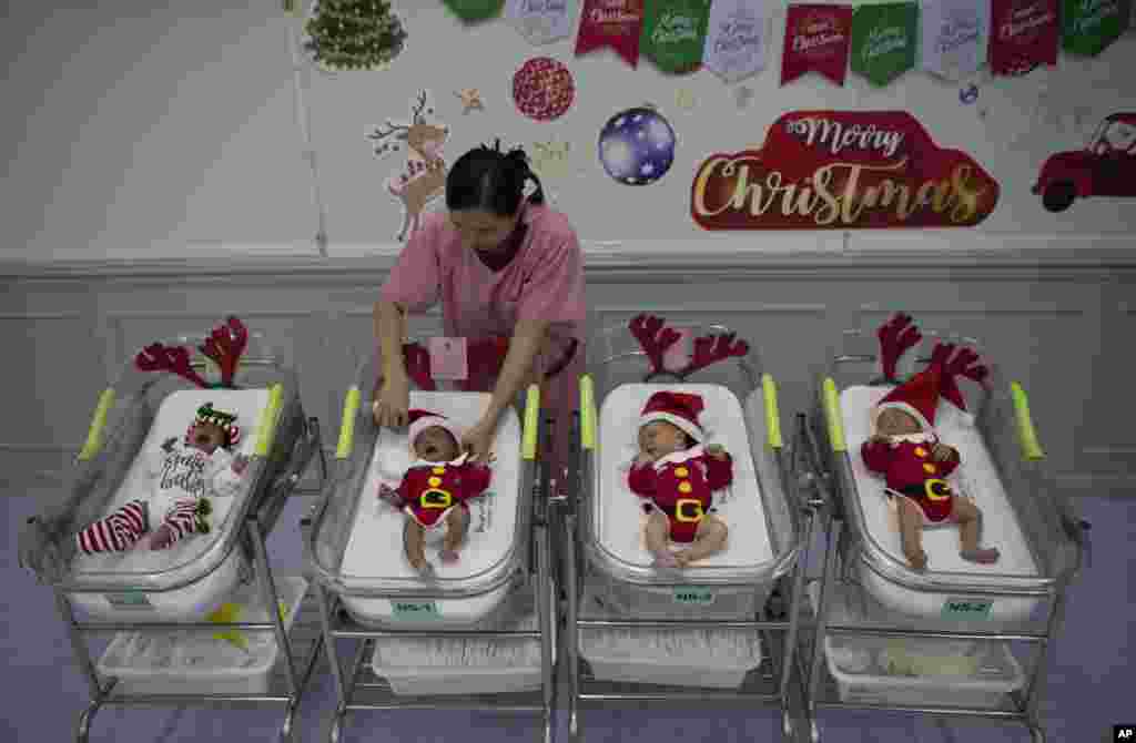 A nurse adjusts the outfits of newborn babies dressed in Santa costumes on Christmas eve at the Synphaet hospital in Bangkok, Thailand, Dec. 24, 2019.