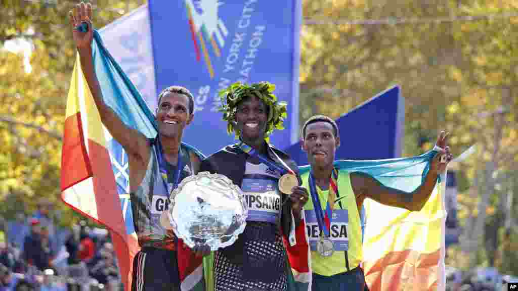 Le vainqueur chez les hommes, Wilson Kipsang, centre, est rejoint par le deuxième au classement, Lelisa Desisa Benti, des États-Unis, à gauche, et le troisième, Gebre Gebremariam, de l&#39;Ethiopie, au terme du 44ème annuel Marathon de New York à New York, le 2 novembre 2014. 