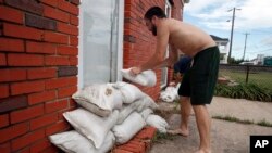 Adam Bazemore places sandbags in the doorways, Tuesday, Sept. 11, 2018, in the Willoughby Spit area of Norfolk, Va., as he makes preparations for Hurricane Florence. (AP Photo/Alex Brandon)