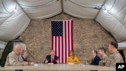 President Donald Trump, accompanied by National Security Adviser John Bolton, third from left, first lady Melania Trump, fourth from right, U.S. Ambassador to Iraq Doug Silliman, third from right, and senior military leadership, speaks to members of the media.