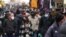 People, some wearing surgical masks, others FFP2 masks, to cope with the surge of COVID-19 cases stroll past stalls at the Porta Portese open air market, in Rome, Jan. 9, 2022. 