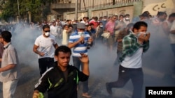 Anti-government and supporters of ousted Egyptian President Mohamed Morsi run after riot police released tear gas along a road at Kornish El Nile, which leads to Tahrir Square, Cairo, October 6, 2013. 