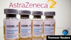 FILE PHOTO: Vials and medical syringe are seen in front of AstraZeneca logo in this illustration