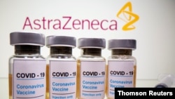 FILE PHOTO: Vials and medical syringe are seen in front of AstraZeneca logo in this illustration