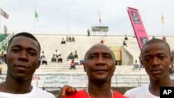 Larry Sawyer and Samba Koroma pose with their coach before a match
against Nigeria's youth team at Freetown's national stadium, 09 Dec 2009