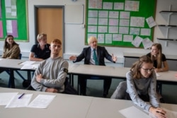 Britain's Prime Minister Boris Johnson sits in class with 11th-graders during a visit to Castle Rock school on the students' first day back, in Coalville, East Midlands, England, Aug. 26, 2020.