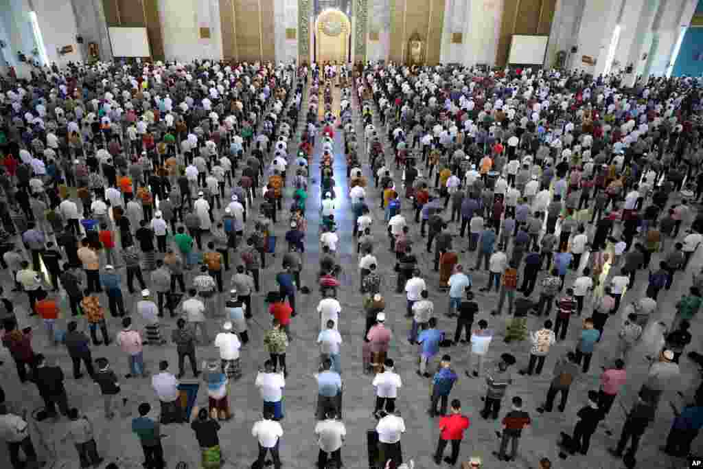 Muslim men perform Friday prayer at the distance of about one meter (3 ft) to each other as a social distancing effort to prevent the spread of new coronavirus outbreak at Al Akbar mosque in Surabaya, East Java, Indonesia. 