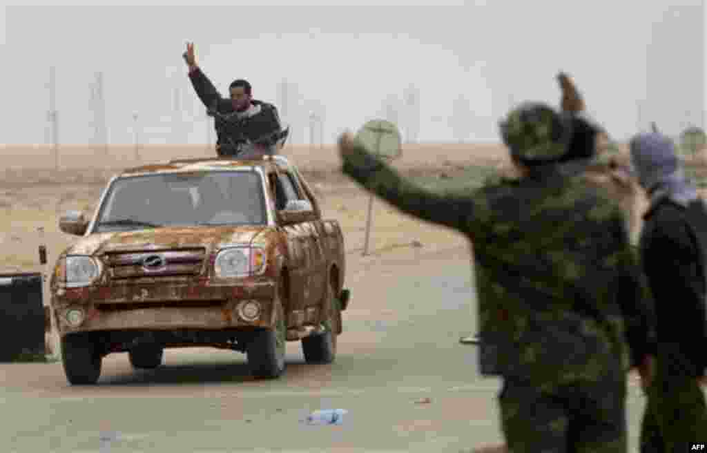 Libyan rebels flash the victory sign as they ride on top of a car with heavy weapons on the frontline near Sultan, south of Benghazi, Libya, Friday, March 18, 2011. The U.N. Security Council voted Thursday to impose a no-fly zone over Libya and authorize 