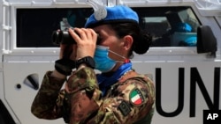 FILE - An Italian UN peacekeeping soldier looks through binoculars on a road that leads to a UN post along the border known as Ras Naqoura where Lebanese and Israeli delegations are meeting, in Naqoura, Lebanon, May 4, 2021.