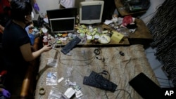 FILE - Members of the National Bureau of Investigation and FBI gather evidence at the home of an American suspected child webcam cybersex operator during a raid in Mabalacat, Philippines. 