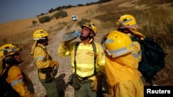 FILE - A firefighter drinks water after extinguishing a forest fire during a heatwave in Benaojan, Spain, July 12, 2017. A new fire burns in a national park.