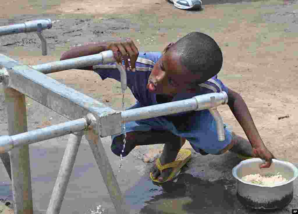 Boy slurps a few drops of water from faucet at Badbaado IDP camp, Mogadishu, Somalia, August 11, 2011. (VOA - P. Heinlein)