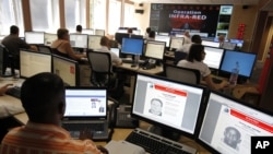 FILE - Interpol employees work in the control room of the Infra-Red operation in Lyon, central France. A Nigerian national identified only as Mike, an alleged leader of an email scamming network, was arrested in Port Harcourt, Nigeria, in June, 2016.