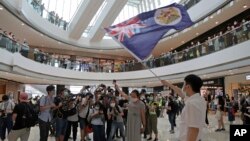 Người biểu tinh chống luật an ninh cầm số hộ chiếu Anh ở nước ngoài (BNO) và giương cao quốc kỳ cũ của Hong Kong hôm thứ Sáu, 29/5/2020. 