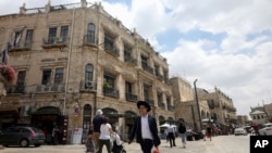 FILE - People walk past the Palestinian-run Imperial Hotel that is part of a legal battle, in Jerusalem's Old City, June 13, 2019. 