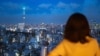 FILE - A woman looks at the city skyline with clouds in the distance at dusk from the Bunkyo Civic Center Observation Deck in Tokyo on August 28, 2024.