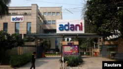 Seorang pria berjalan melewati kantor Adani Group di Gurugram, India, 22 November 2024. (Foto: Priyanshu Singh/Reuters)