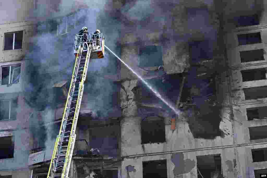 Ukrainian rescuers work to extinguish a fire in a residential building following a missile attack in Kharkiv.