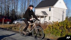 La enfermera Kaci Hickox pasea en su bicicleta en una carretera rural de Fort Kent, Maine, en desafío a su cuarentena.