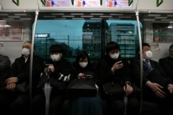 Commuters wearing masks sit on a train in Tokyo, March 2, 2020.