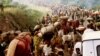 FILE - Rwandese refugees cross Rusumo border to Tanzania from Rwanda carrying their belongings even goats, mattresses and cows, May 30, 1994.