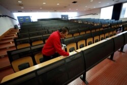 FILE - A man cleans an empty classroom at Bicocca University in Milan, Italy, March 2, 2020. Italian authorities have closed schools and universities in Lombardy and northern regions to prevent the spread of the coronavirus.