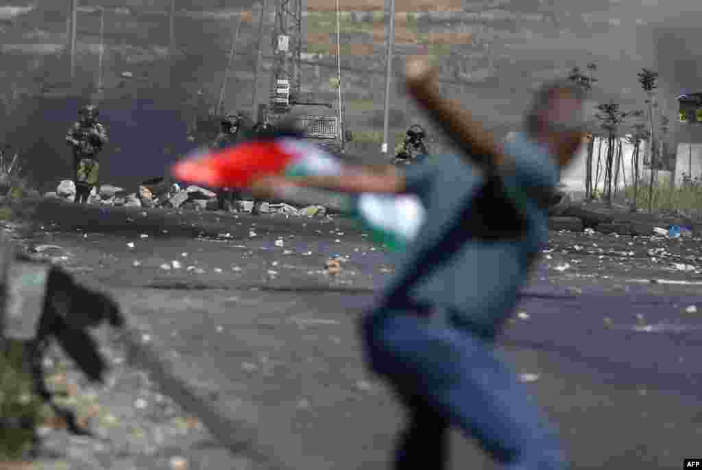 A Palestinian demonstrator hurls a rock toward Israeli forces during clashes near the Jewish settlement of Beit El near Ramallah in the occupied West Bank.