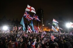 FILE - People wave the British Union Jack and England flags as they celebrate in Parliament Square on Brexit day in London, Britain, Jan, 31, 2020.
