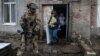 (FILE) Members of a local election commission, accompanied by a serviceman, visit voters during early voting in Russia's presidential election in Donetsk, Ukraine.