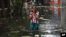 Seorang wanita ketika mengarungi air banjir di Jakarta, Indonesia, Sabtu, 4 Januari 2020. Hujan dan naiknya sungai merendam sebagian wilayah Jakarta dan menyebabkan tanah longsor di kabupaten Bogor dan Depok di pinggiran kota. (Foto: AP)