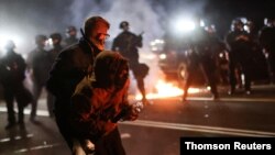A protester is helped by another to retreat after clashing with the police on the 100th consecutive night of protests against police violence and racial inequality, in Portland, Oregon, Sept. 5, 2020.