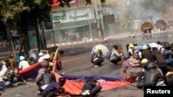 Para pengunjuk rasa berjongkok setelah polisi melepaskan tembakan untuk membubarkan aksi protes anti-kudeta di Mandalay, Myanmar, 3 Maret 2021. Di antara mereka, Angel (kiri), yang juga dikenal sebagai Kyal Sin, berlindung sebelum dia tertembak di kepala. (REUTERS / Stringer)
