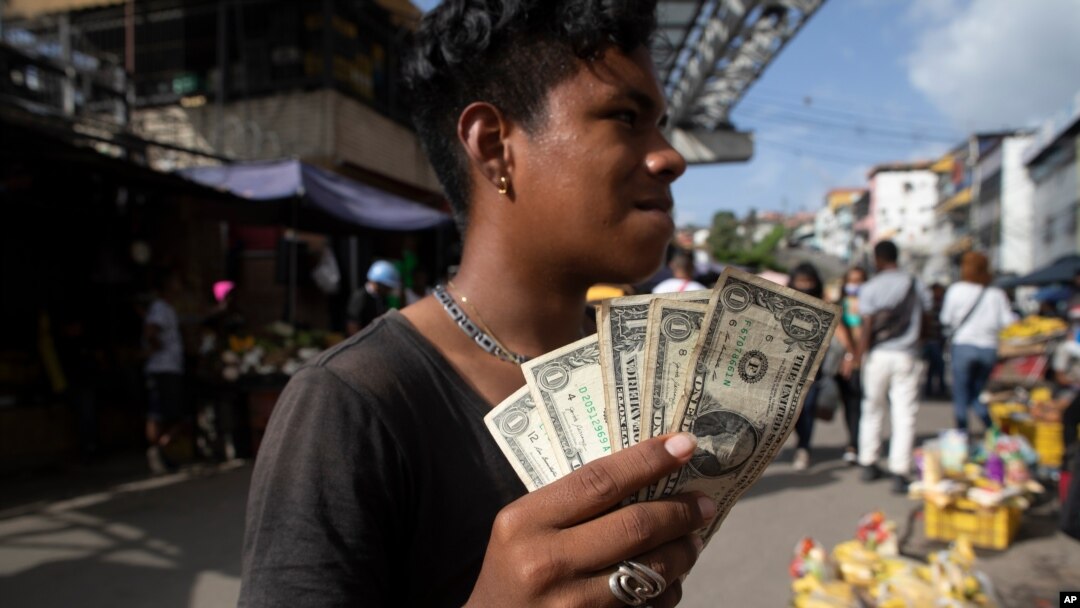 Un joven muestra sus billetes de un dólar en un mercado en Caracas, el 11 de junio de 2021. 