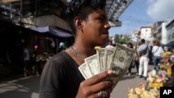 Un joven muestra sus billetes de un dólar en un mercado en Caracas, el 11 de junio de 2021. 