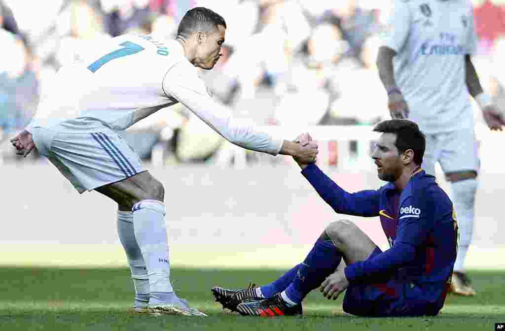 Cristiano Ronaldo du Real Madrid, aide le Barcelonais Lionel Messi à se remettre sur pied lors du match de football de la Liga espagnole entre le Real Madrid et Barcelone à Madrid, le 23 décembre 2017.