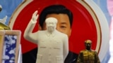 Sculptures of the late Chinese Chairman Mao Zedong are placed in front of a souvenir plate featuring a portrait of Chinese President Xi Jinping at a shop next to Tiananmen Square in Beijing, China, March 1, 2018. 