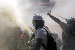 A protester uses a slingshot as demonstrators clash with riot police officers during a protest against the military coup in Yangon, Myanmar, Feb. 28, 2021.