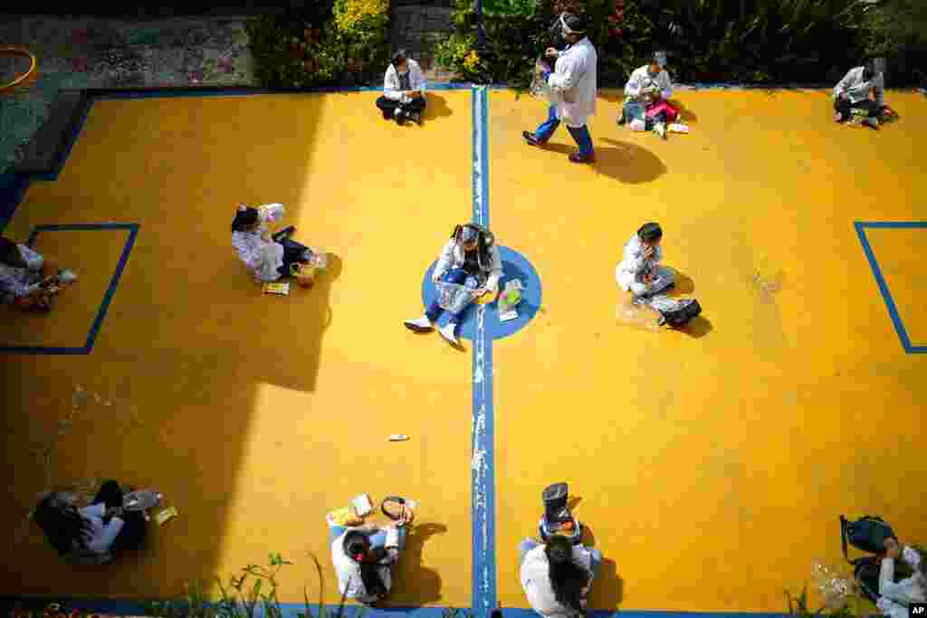 Students wearing COVID-19 protective gear social distance during snack time on their first day back to in-person class since March 2020 at Liceo Lunita, a private school in Chia on the outskirts of Bogota, Colombia.