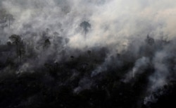 FILE - An aerial view shows smoke from a burning tract of Amazon jungle as it is cleared by loggers and farmers near Porto Velho, Brazil, Aug. 29, 2019.