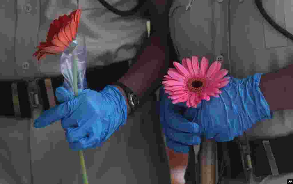 Security officers hold flowers given to them as a gesture of gratitude at the end of a free medical camp in Dharavi, one of Asia&#39;s biggest slums, in Mumbai, India.