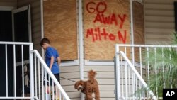 Noah Weibel y su perro Cookie suben los escalones de su casa mientras su familia se prepara para el huracán Milton el lunes 7 de octubre de 2024, en Port Richey, Florida.