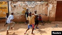 FILE - Children play in the street in Kisenyi, a slum in Kampala.