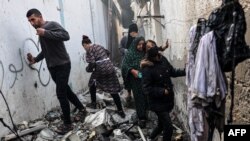 FILE — People find their way through a rubble-covered alley, following overnight Israeli bombardment in Rafah in the southern Gaza Strip on February 25, 2024, amid continuing battles between Israel and the Palestinian militant group Hamas.