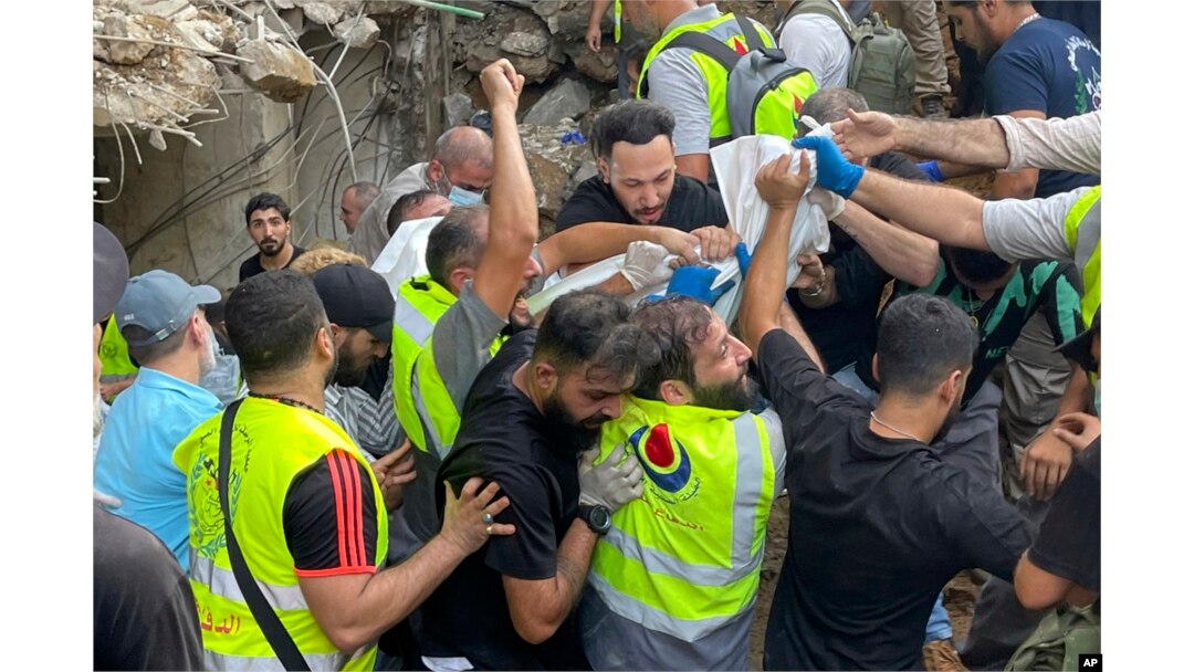 Rescuers carry a body at the scene of a missile strike in the southern suburbs of Beirut, Sept. 20, 2024.