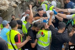 Rescuers carry a body at the scene of a missile strike in the southern suburbs of Beirut, Sept. 20, 2024.