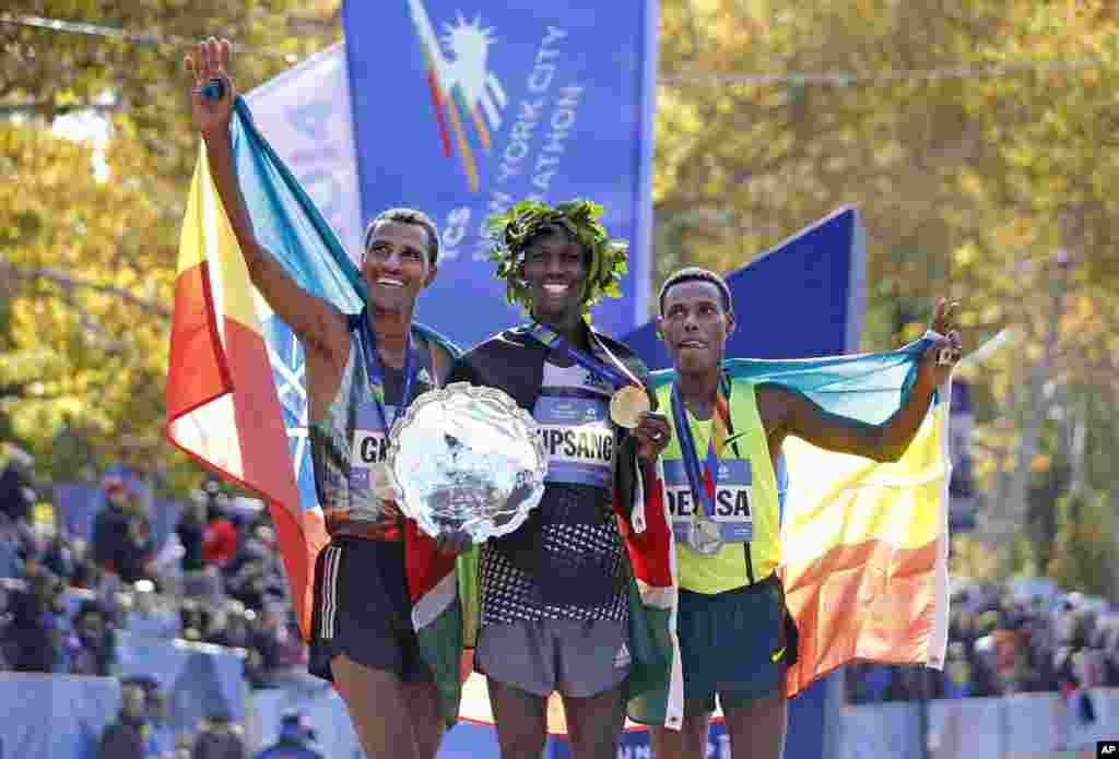 Men's winner Wilson Kipsang, center, is joined by second-place finisher Lelisa Desisa Benti, of the United States, left, and third place finisher Gebre Gebremariam, of Ethiopia, after the 44th annual New York City Marathon in New York, Nov. 2, 2014. 