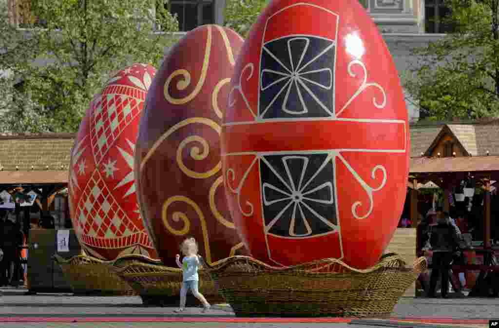 Seorang anak berjalan antara telur-telur Paskah raksasa di sebuah pameran di Bucharest, Rumania. Sebelum Paskah, yang dirayakan oleh baik umat Ortodoks atau Katolik pada 16 April, sebuah pameran Paskah diselenggarakan di luar istana yang dibangun oleh almarhum pemimpin Komunis Nicolae Ceausescu.