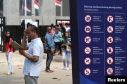 A man stands next to a sign showing prohibited items at a gate of the Gelora Bung Karno sports complex, ahead of the 2018 Asian Games in Jakarta, Indonesia, Aug. 17, 2018.