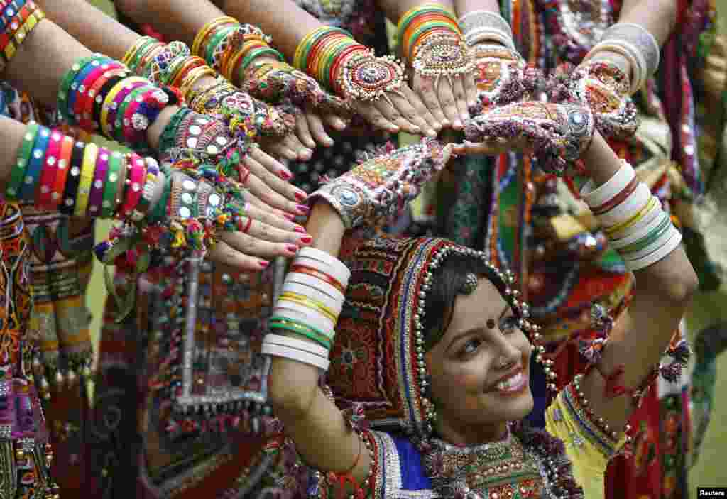 Seorang perempuan India memakai pakaian tradisional, dikelilingi oleh rekan-rekannya, dalam latihan menari "garba", menjelang festival keagamaan Navratri, di Ahmedabad, India barat. 