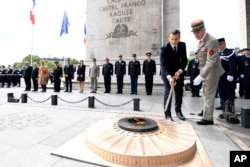 President Emmanuel Macron light up the flame on the Unknown Soldier's tomb at the Arc of Triomphe after his formal inauguration ceremony as French President in Paris, May 14, 2017.